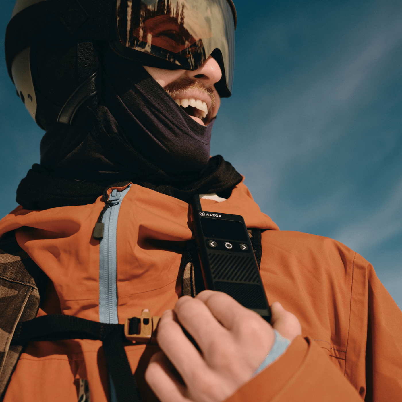 Snowboarder using Aleck Off Grid walkie talkie integrated with Aleck Nunchucks for seamless communication and music on the mountain
