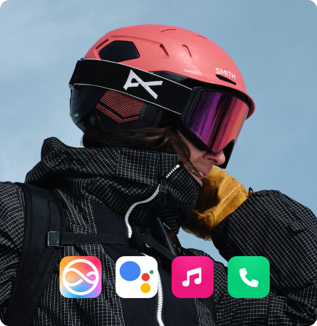 Skier wearing helmet with Aleck 006 audio system, pressing button to control music or calls