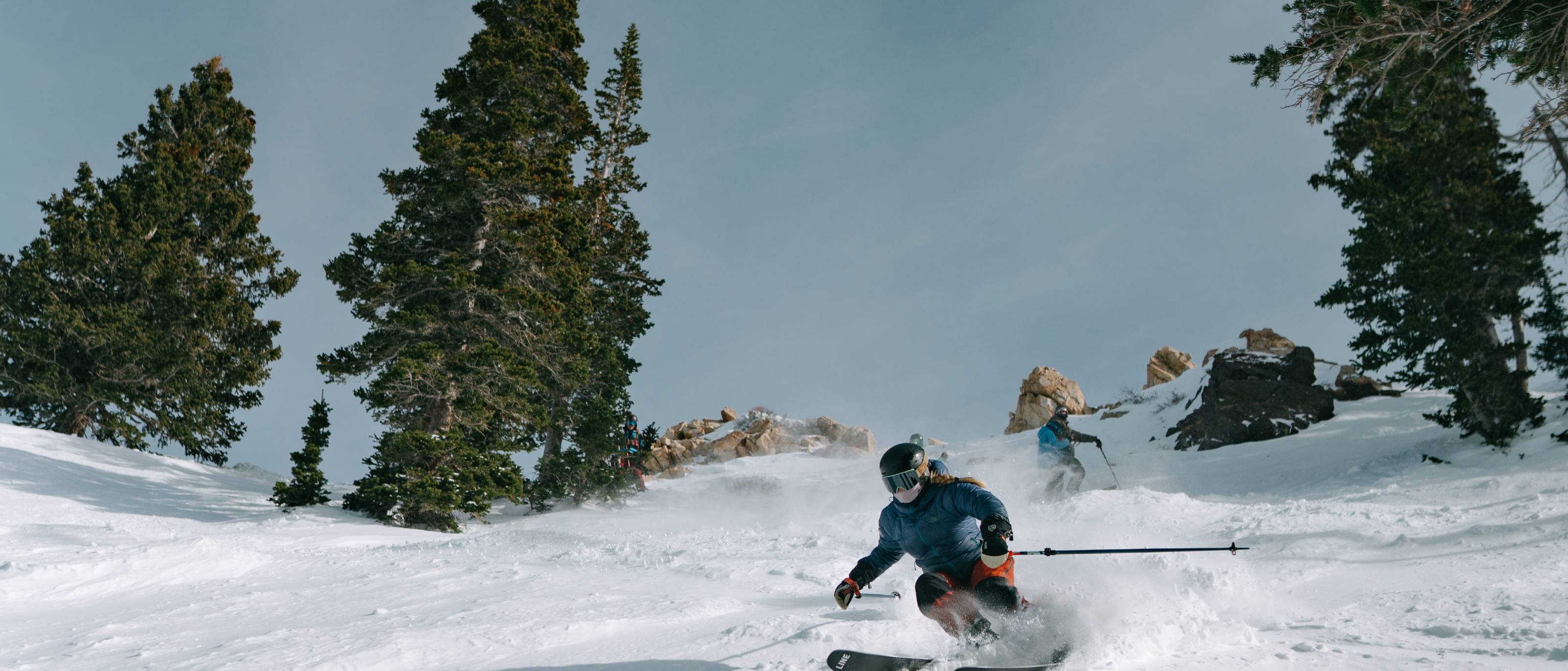 Skier riding downhill with Aleck helmet audio gear in snowy mountain