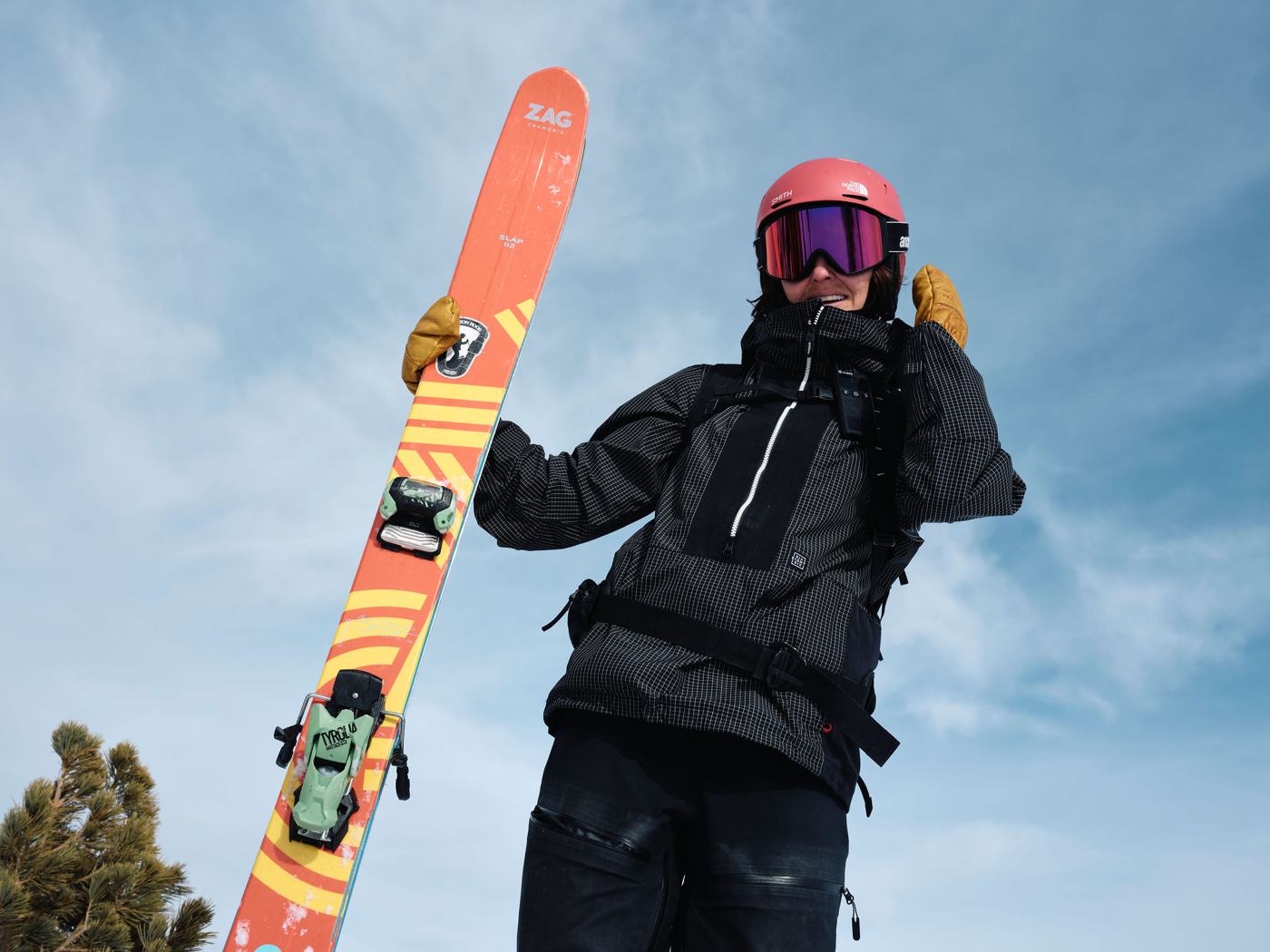 Skier shouldering skis under a blue sky