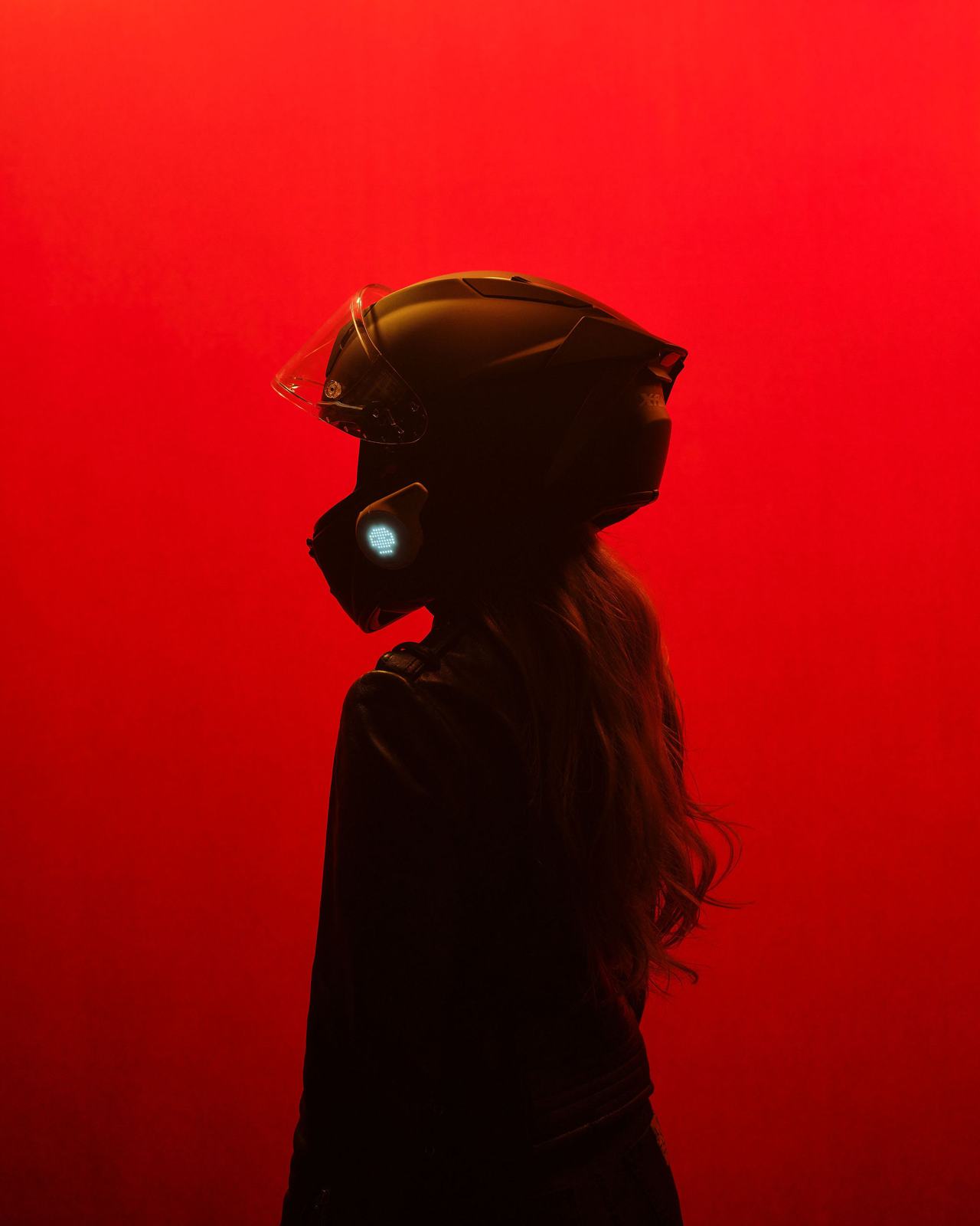 Motorcyclist in a full-face helmet with a glowing 99ONE Rogue, lit in red